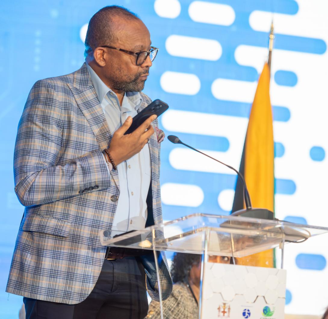 Director of Tourism, Donovan White uses his cell phone to converse with the Jamaica Tourist Board’s artificial intelligence (AI) - powered Chatbot ‘Cynthia’ to demonstrate one of the many ways in which AI can be used in tourism, during his presentation on “Harnessing AI for Tourism Resilience” at the 3rd Global Tourism Resilience Conference, held recently at the Princess Grand Jamaica resort, Hanover. While welcoming the benefits of AI, Mr. White maintained that the human element of travel is irreplaceable.