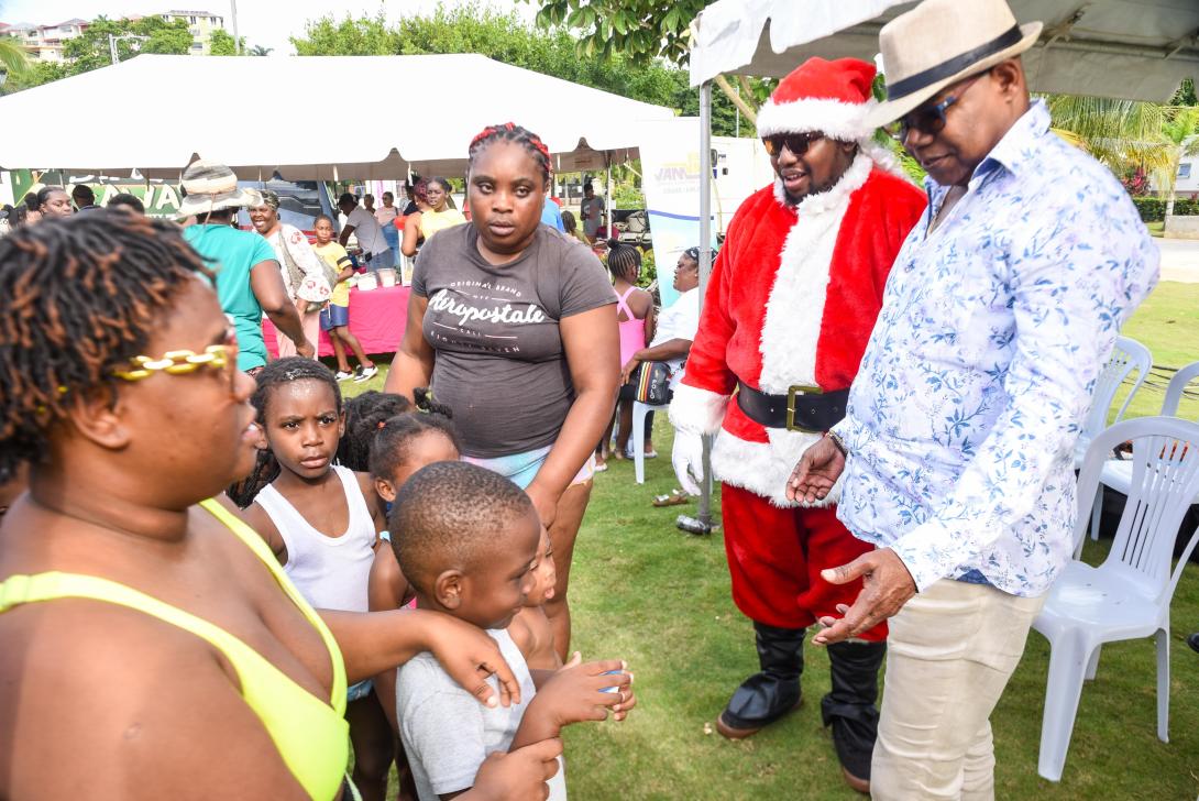 Minister of Tourism, Hon Edmund Bartlett (R) engaging with children ahead of the toy distribution by Santa (L) at the Christmas Treat held by the Ministry of Tourism and its public bodies at Harmony Beach Park in Montego Bay on Sunday, December 22, 2024.